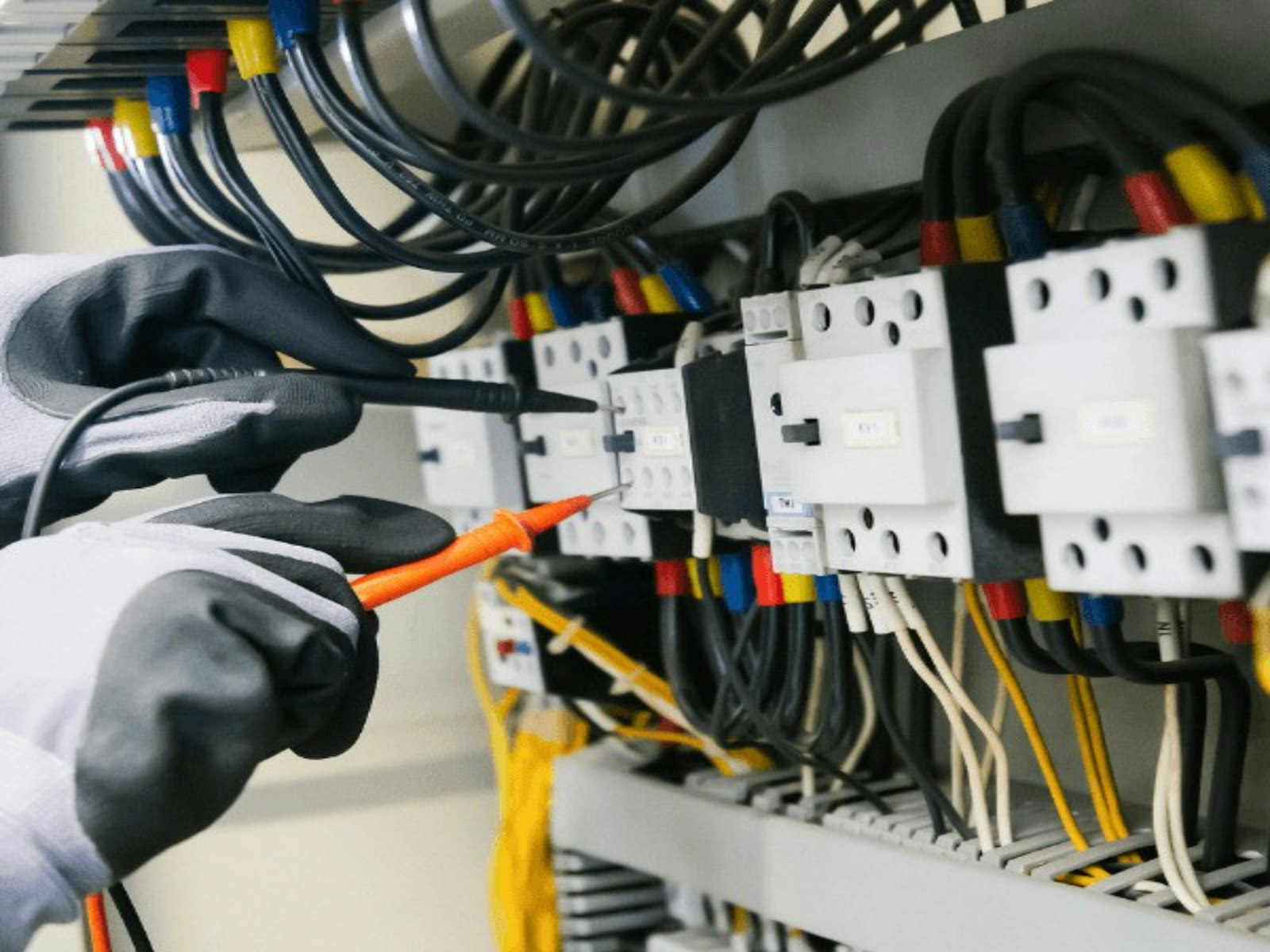 Electrician testing wiring inside a commercial control panel