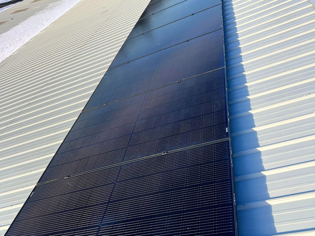 Row of solar panels along the ridge of a metal roof