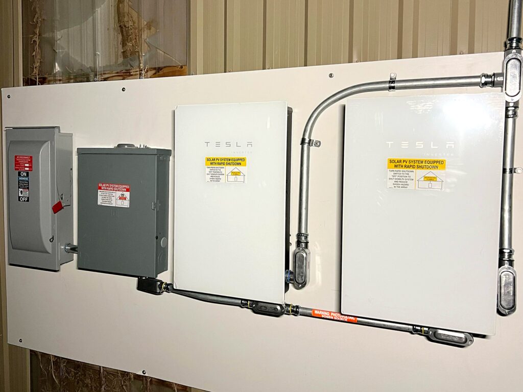Two Tesla solar inverters, AC disconnect and rapid shutdown switch mounted on a board