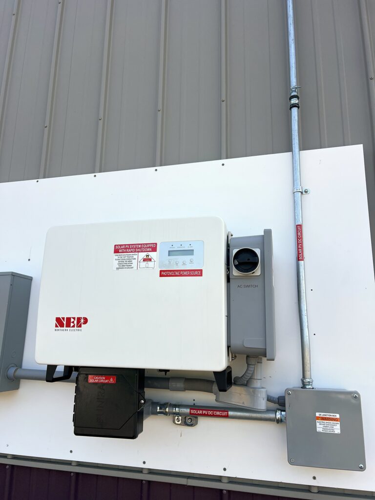 Solar inverter with rapid shutdown and labeled PV conduit on the building wall