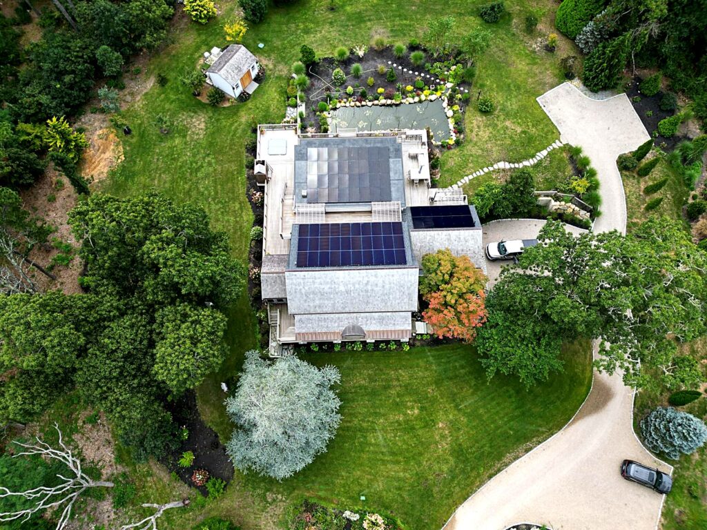 Aerial view of a Brewster, MA home with rooftop solar panels on three roof sections