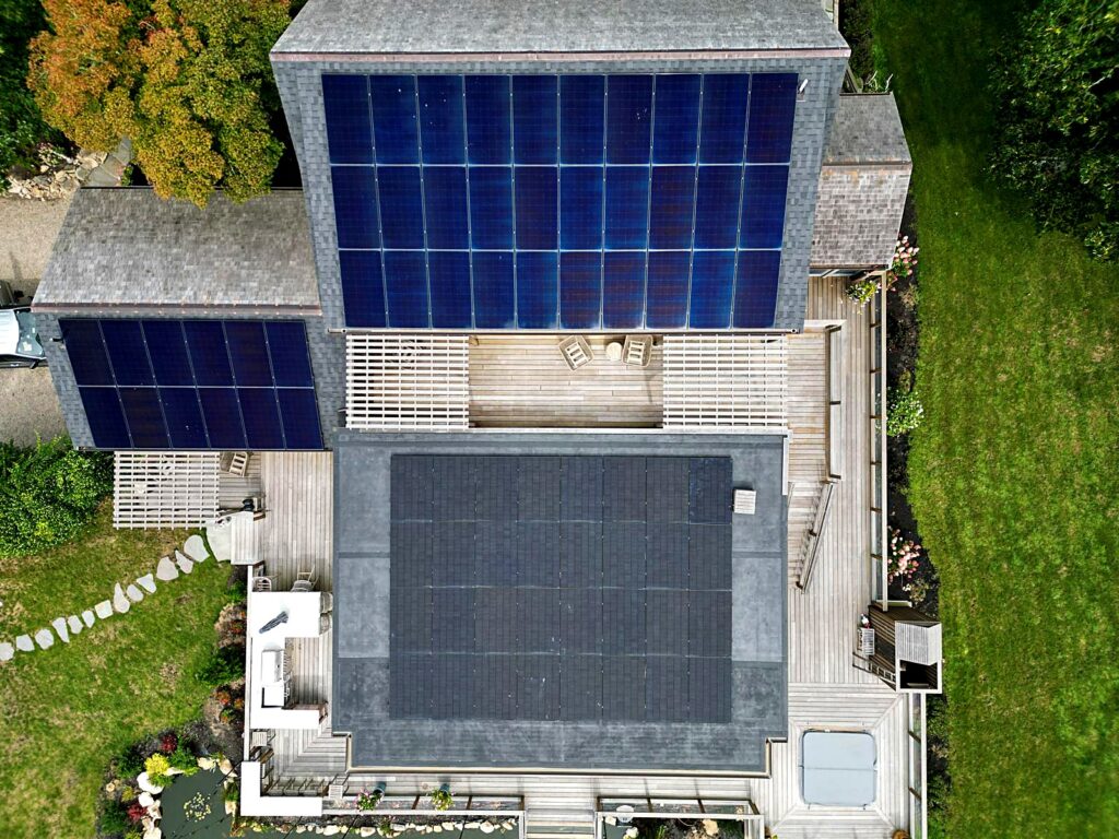 Top-down drone view of three residential solar arrays in Brewster, MA
