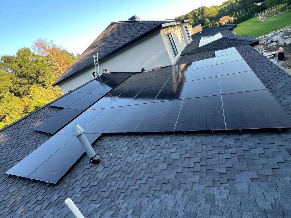Black residential solar panels on an asphalt shingle roof of a new home