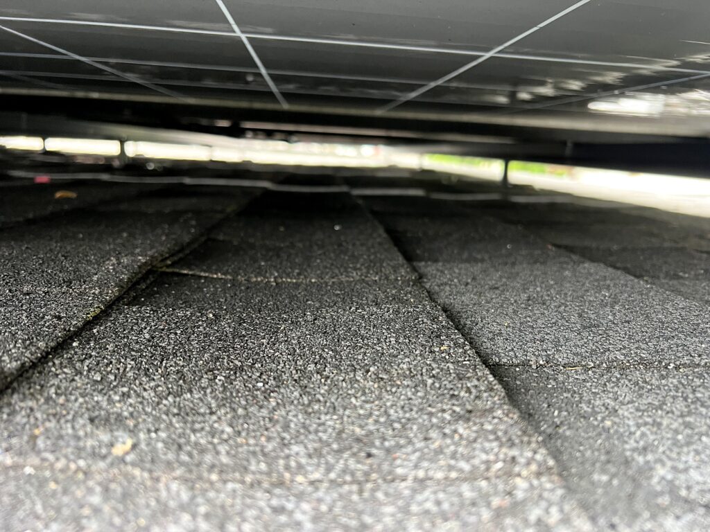 View under the solar panels showing mounting clearance above the roof shingles