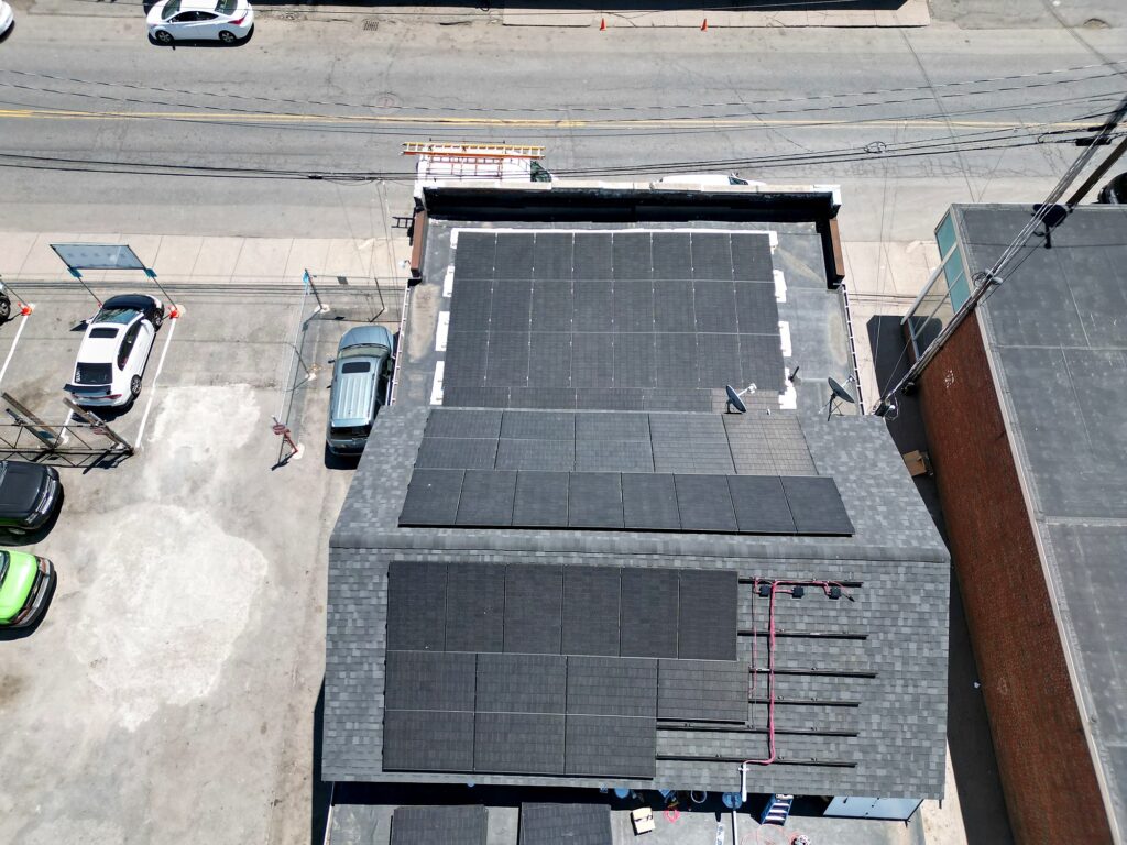 Drone view of Valencia Auto Repair in Framingham, MA, with solar arrays on the flat and pitched roof