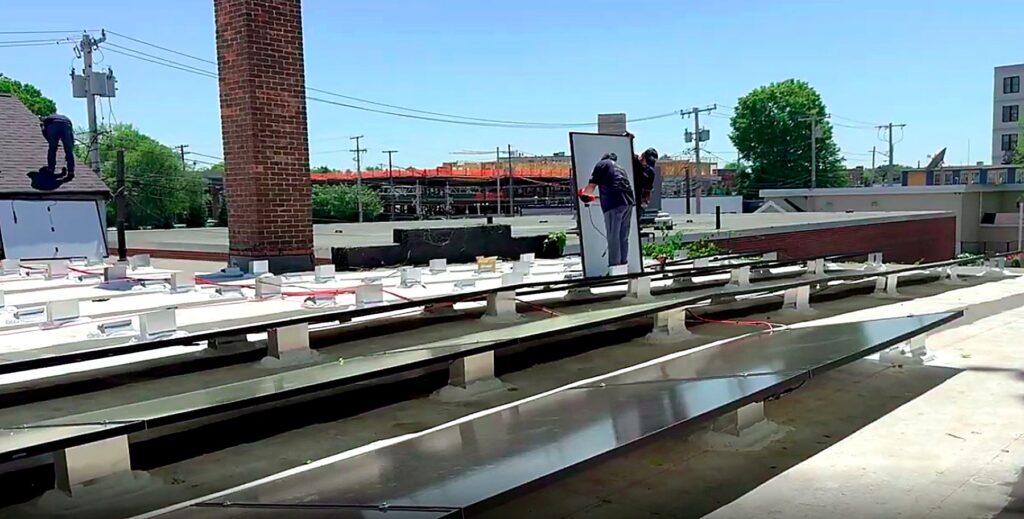 Crew installing racking and solar modules around the brick chimney